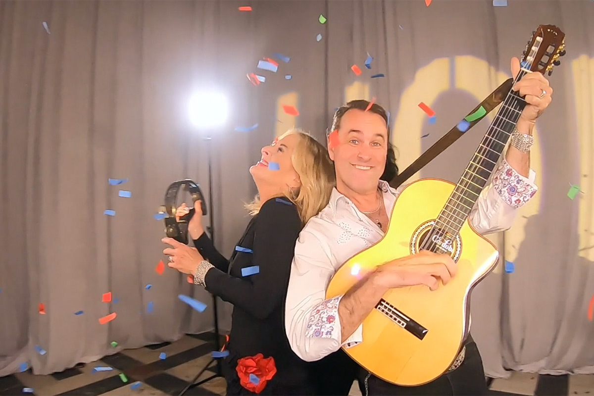 A man with a guitar and a women with a tambourine smile in the 360 video booth