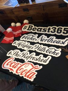 Custom Coca-Cola prop signs and pom pom hats outside the photo booth