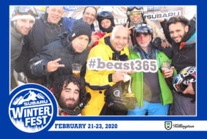 Group holding a #beast365 sign posing in the branded backdrop photo booth with a Subaru Winter Fest frame