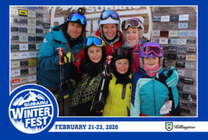 Family in skiing gear posing in the branded backdrop photo booth with a Subaru Winter Fest frame
