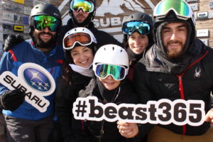 Group holding Subaru and #beast365 signs posing in the Subaru branded backdrop photo booth