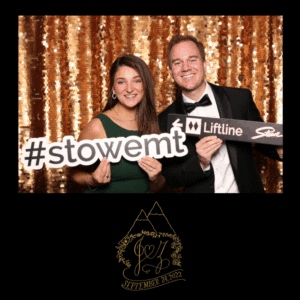 A couple in a open air photo booth holding and wearing props