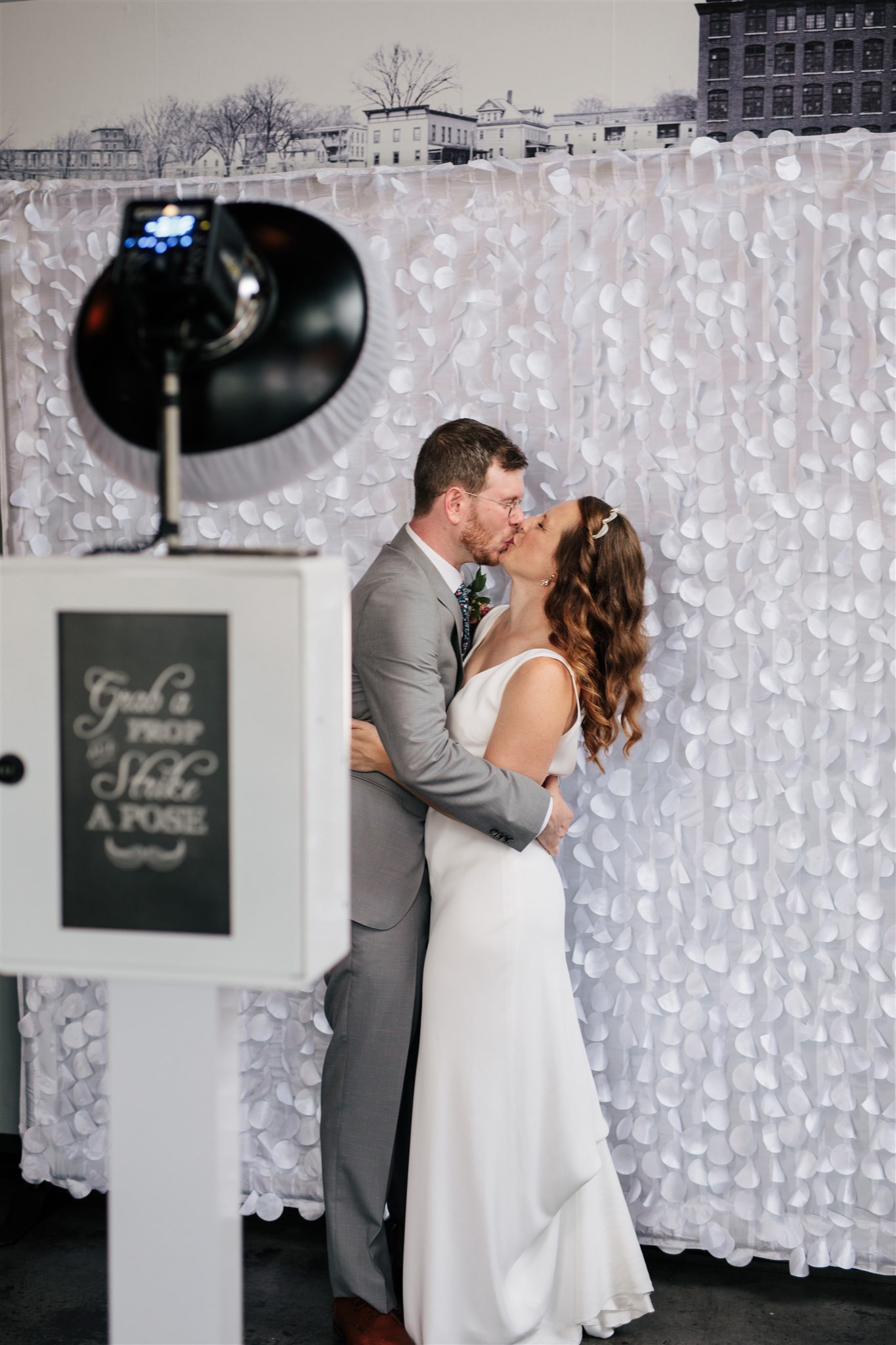 wedding couple kisses in front of the backdrop of the wedding photo booth